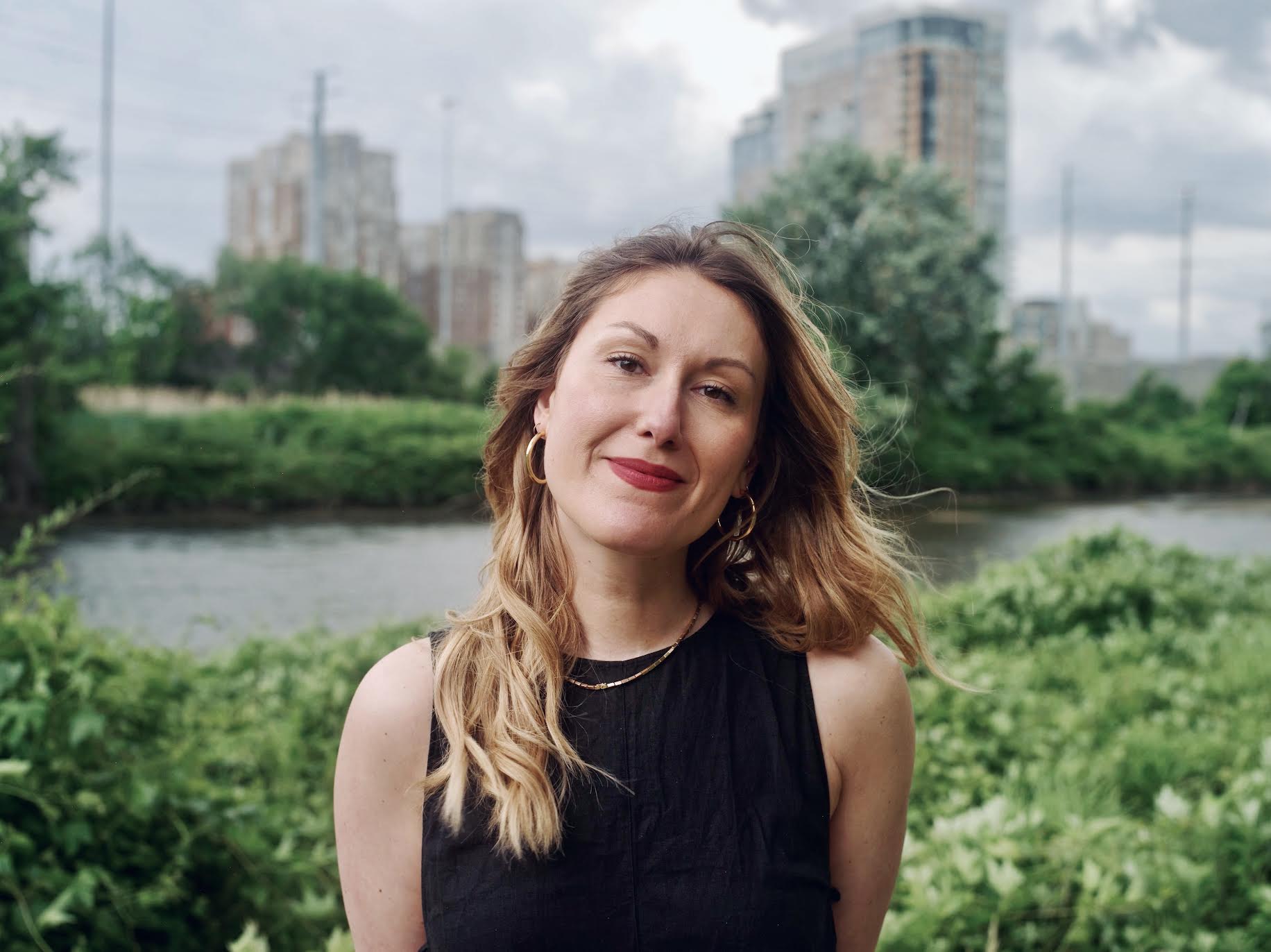 Clea Massiani standing in leafy landscape with tower residences rising in the background