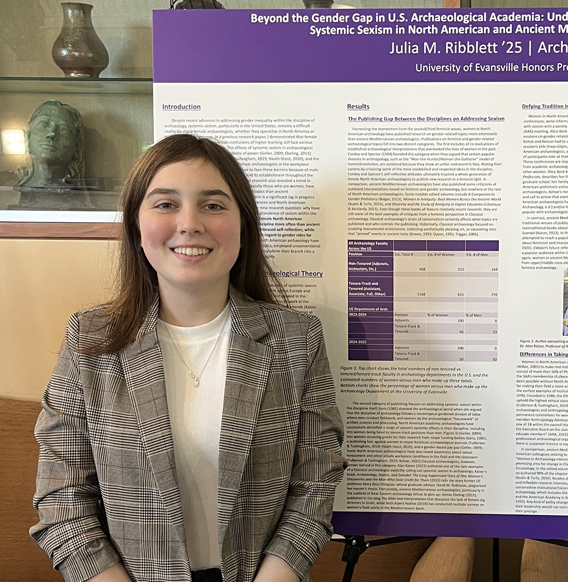 Julia Ribblett standing before her poster at a conference in a room with ancient artifacts on shelves