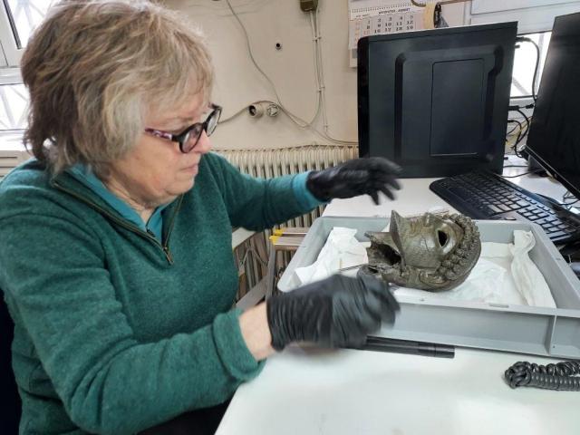 Carol Mattusch examines ancient bronze head in conservation lab