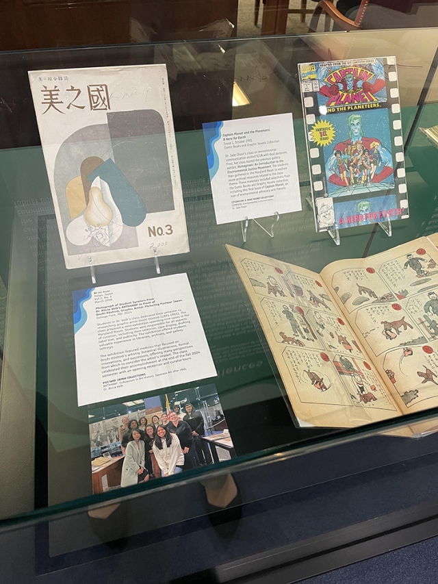 A display of pictures, open books, and posters, with text panel, in a glass case in an exhibition